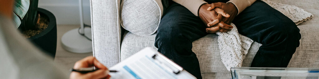 Person sitting on a couch across from someone else holding a clipboard