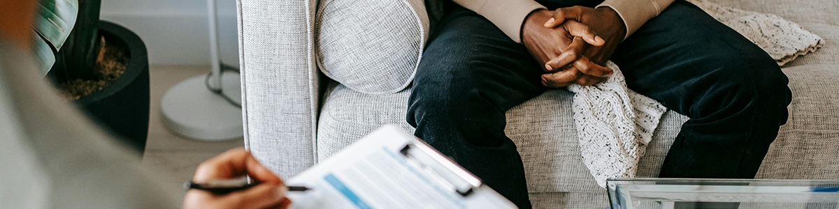 Person sitting on a couch across from someone else holding a clipboard