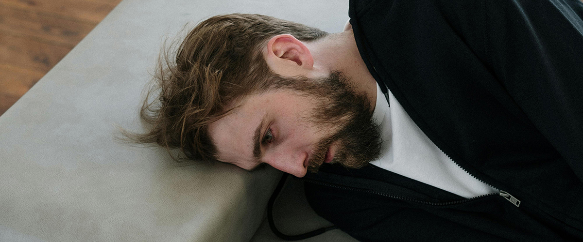 man laying on bed with a blank stare