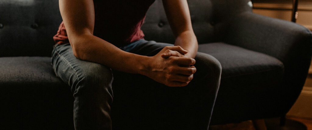 Man sitting on a couch with his hands folded